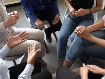 Top close up view in circle sit people, corporate teambuilding activity solve issues talk think together or alcohol rehab addiction treatment, twelve-step program, physical, mental, spiritual concept