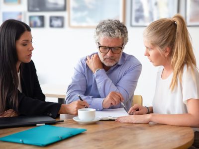 Family legal advisor explaining document details to mature father and adult daughter. Medium shot. Expertise or paperwork concept